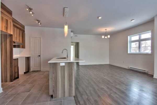 Vaste espace de vie lumineux avec cuisine moderne, sol en bois et fenêtres panoramiques pour un confort optimal et une gestion immobilière efficace.