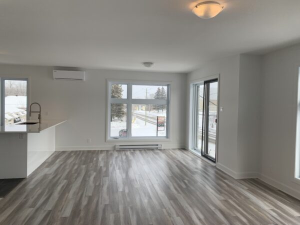 Appartement lumineux avec grandes fenêtres et balcon.