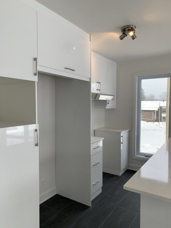 Cuisine moderne avec rangements blancs, espace lumineux et vue sur la neige à Mirabel, secteur St-Canut, parfait pour un logement de 2 chambres.