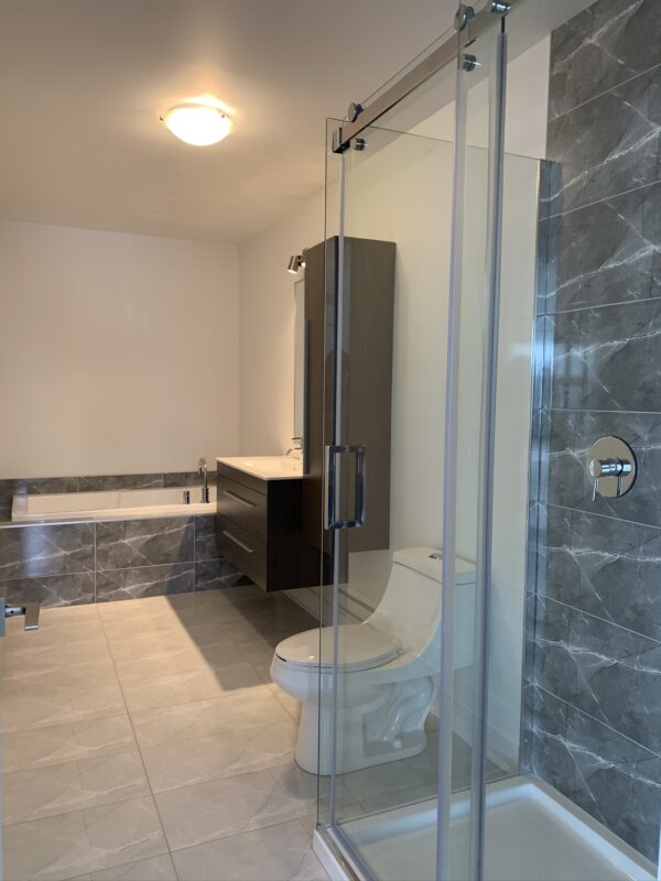 Salle de bain moderne avec douche en verre, toilette et espace lavabo dans un logement de 2 chambres à Mirabel, secteur St-Canut, disponible à partir du 1er juillet.