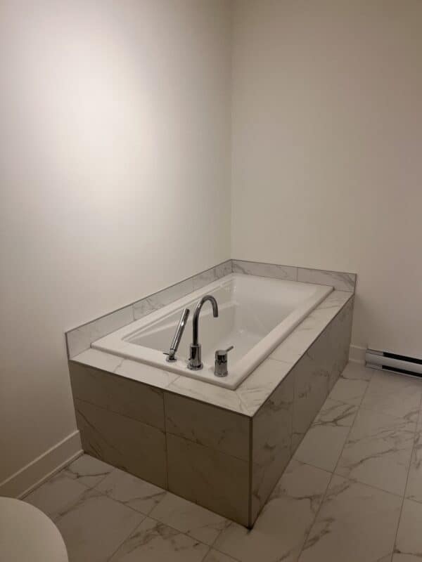 Salle de bain avec baignoire balnéo moderne, finition en marbre, idéale pour gestion immobilière résidentielle et commerciale.