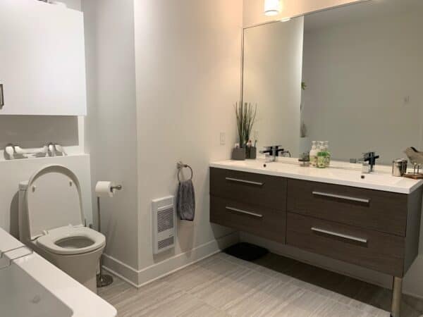 Salle de bain élégante avec double lavabo, grand miroir, et rangement pratique, optimisant la confort et la style pour la gestion immobilière professionnelle.