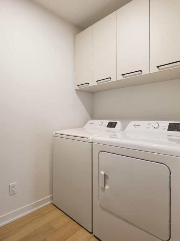 Élément de buanderie avec lave-linge et sèche-linge blancs, rangement mural pratique, espace propre et organisé, idéal pour un appartement 2 chambres à Joliette.