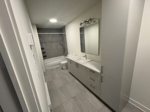 Salle de bain contemporaine avec baignoire, lavabo et miroir dans un appartement à Lachute, idéal pour un logement de 2 chambres disponible dès maintenant.