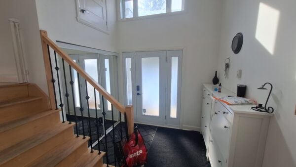 Intérieur lumineux d'un appartement de 3 chambres à louer à Saint-Calixte, avec entrée principale, escalier en bois, et espace de rangement moderne.