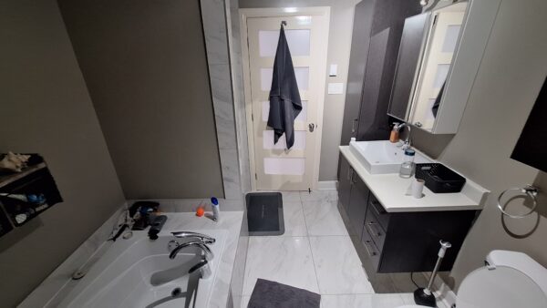 Vue intérieure d'un appartement de 3 chambres à louer à Saint-Calixte, avec salle de bain moderne, lavabo, miroir, et espace de rangement.