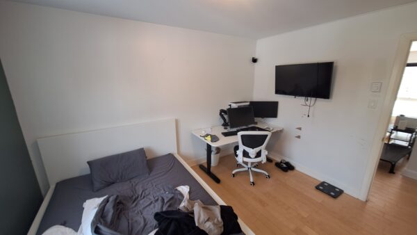 Intérieur d'un appartement avec chambre, espace de travail et télévision, idéal pour location à Saint-Calixte.