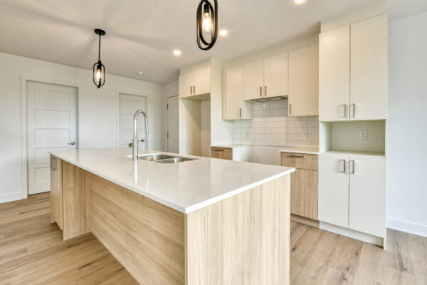 Appareil photo capturant une cuisine lumineuse et contemporaine avec îlot central dans un appartement de Saint-Charles-Borromée.