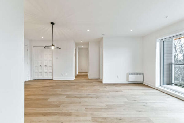 Appartement lumineux avec grandes fenêtres et parquet en bois.