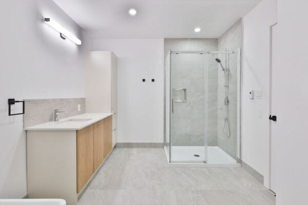 Salle de bain moderne avec douche vitrée et espace fonctionnel.