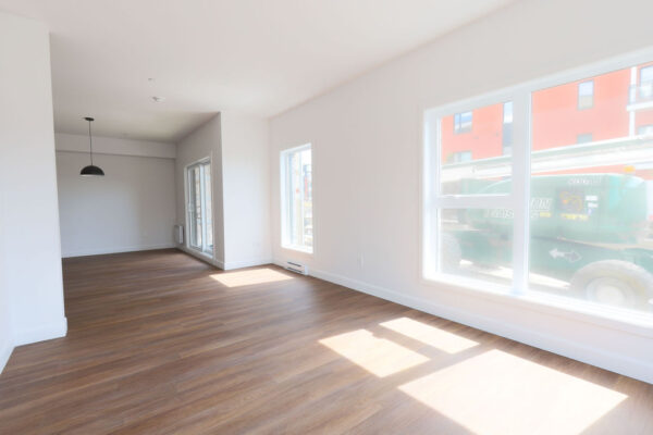 Appartement lumineux avec grandes fenêtres et sol en bois.