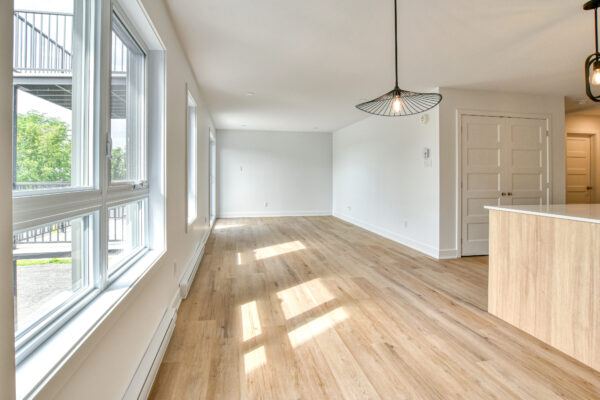 Balcon lumineux avec vue sur l'extérieur, parquet en bois clair, espace ouvert et moderne, idéal pour un appartement à Saint-Charles-Borromée.