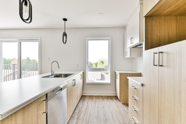 Conception moderne d'une cuisine lumineuse avec îlot central, idéale pour un appartement de deux chambres à Sainte-Julienne, disponible en juillet.