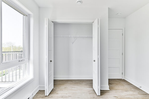 Placard intégré dans un appartement moderne avec espace de rangement, fenêtres lumineuses et sol en bois clair, idéal pour un logement de trois chambres à Sainte-Julienne.