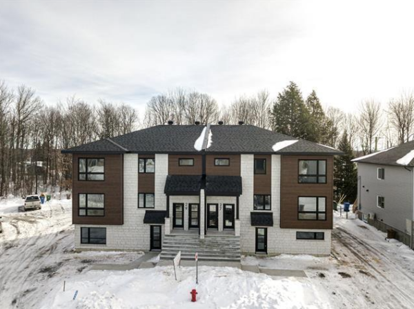 Immeuble résidentiel moderne avec 3 chambres à Brownsburg-Chatham, situé dans un environnement paisible avec neige, arbres et accès facile.