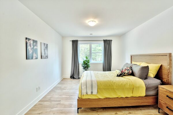 Chambre spacieuse avec lit double, fenêtres lumineuses et décoration moderne dans un appartement à Rawdon.