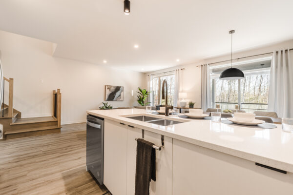 Appartement moderne avec cuisine ouverte et grandes fenêtres offrant une vue dégagée. Parfait pour une famille ou un professionnel recherchant confort et espace à Mirabel.
