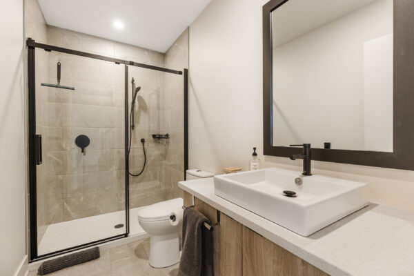 Appartement moderne avec salle de bain élégante et douche en verre.