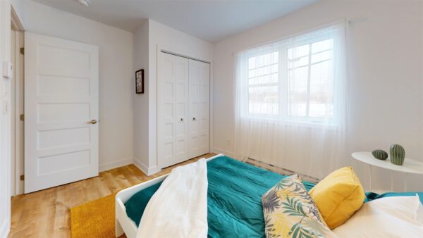 Vue intérieure d'une chambre spacieuse avec fenêtres lumineuses, mobilier moderne et décoration épurée, idéale pour un appartement de 3 chambres à Saint-Charles-Borromée.