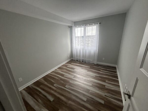 Chambre à coucher moderne dans un appartement de Mirabel, idéal pour famille ou professionnel, avec grande fenêtre laissant entrer beaucoup de lumière naturelle.