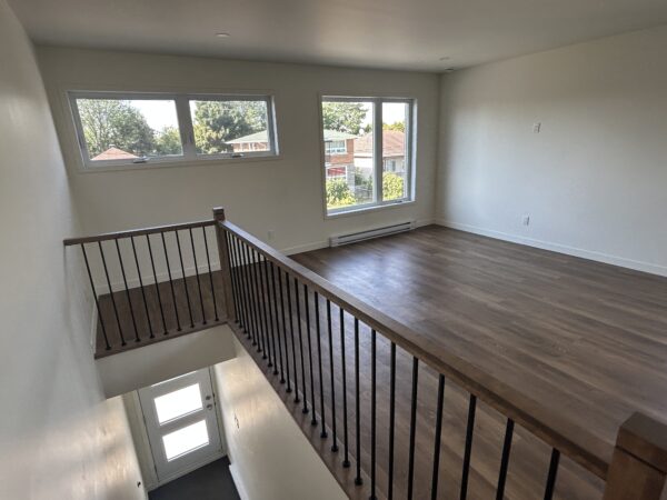 Appartement lumineux avec grandes fenêtres, espace ouvert, et sol en bois, idéal pour location à Saint-Jérôme.