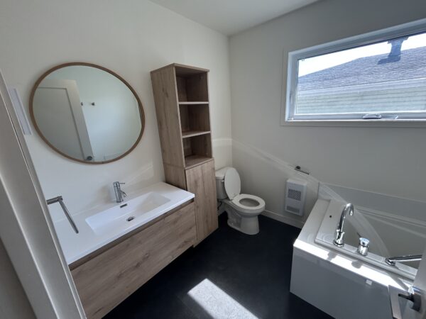Appartement avec salle de bain moderne et espace lumineux.