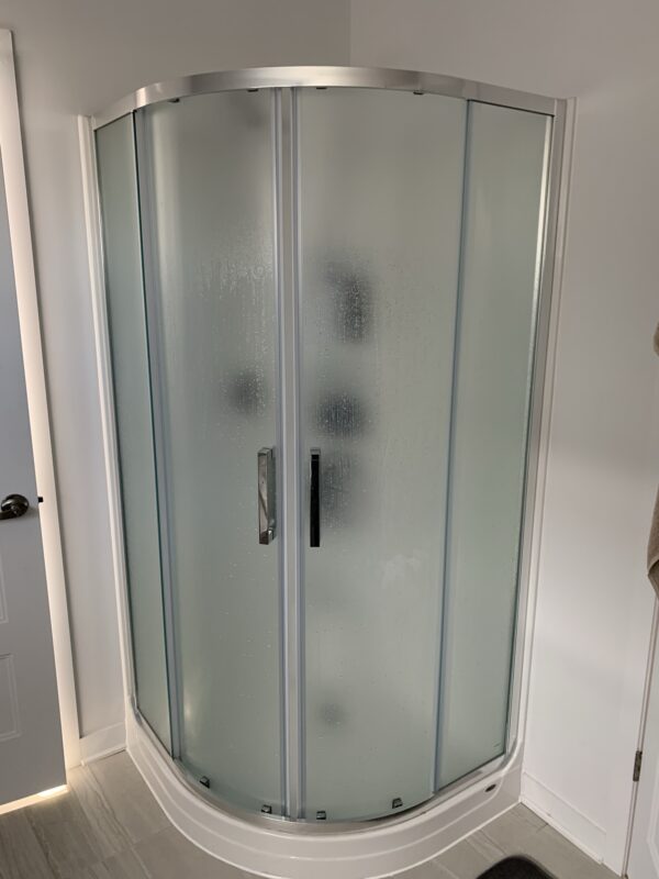 Porte de douche en verre dans un appartement à Mirabel, idéal pour la gestion immobilière. Confort et modernité pour un logement fonctionnel et accueillant.