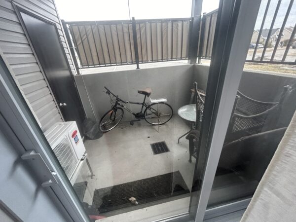 Balcon d'appartement avec vélo, table et chaises, vue sur l'extérieur à Lachute. Idéal pour gestion immobilière et location.