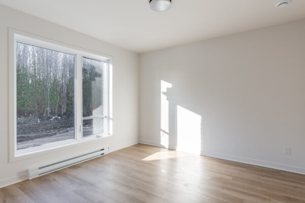 Appartement 2 chambres lumineux à Brownsburg-Chatham, disponible en juillet, avec grande fenêtre offrant une vue sur la nature, idéal pour un logement confortable et moderne.