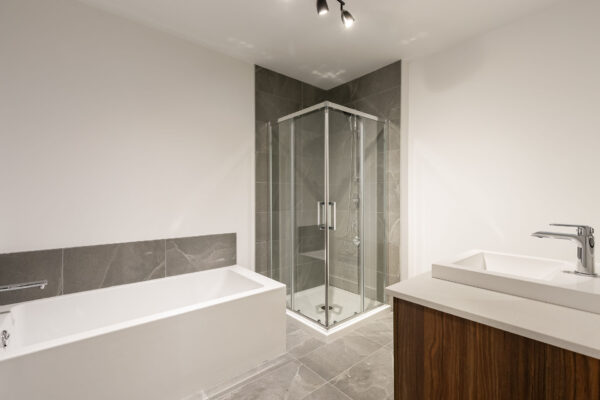 Baignoire et douche dans une salle de bain contemporaine à Saint-Jérôme, idéale pour un appartement 2 chambres en juillet.