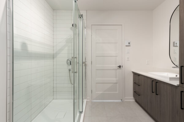 Salle de bain moderne avec douche vitrée et meuble de rangement.