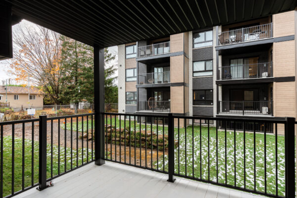Balcon privé avec vue sur l'immeuble résidentiel à Saint-Jérôme, idéal pour profiter de l'été.