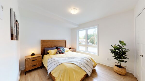 Chambre lumineuse avec lit double, grande fenêtre et décoration moderne dans un appartement de Saint-Charles-Borromée.