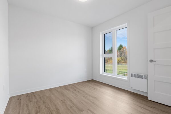 Appartement 2 chambres lumineux à Lachute, idéal pour famille ou professionnel, avec grandes fenêtres offrant une vue sur la nature, situé dans un immeuble moderne et bien entretenu.