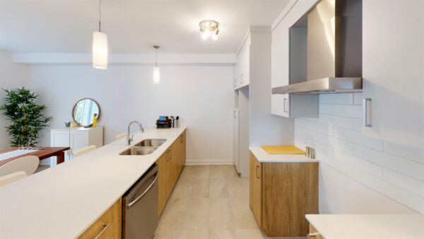 Cuisine moderne avec comptoir en quartz, armoires en bois clair, appareils en acier inoxydable, espace lumineux et fonctionnel dans un appartement de Saint-Charles-Borromée.