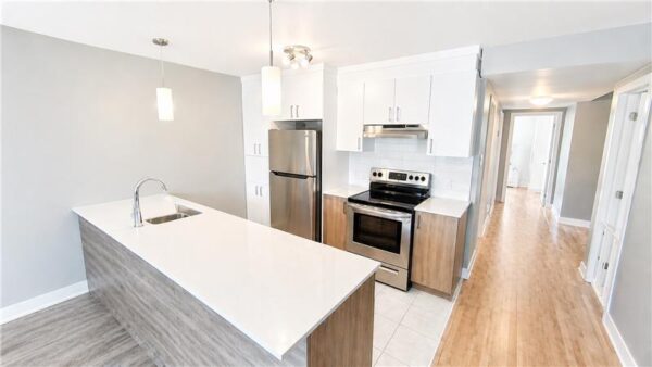Cuisine moderne avec îlot central dans un appartement de 2 chambres à Joliette, idéal pour la gestion immobilière.