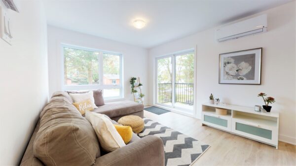 Vue lumineuse d'un appartement de 2 chambres à Saint-Charles-Borromée, avec salon moderne, grande fenêtre et balcon offrant une belle luminosité.