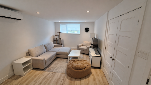 Balcon avec vue sur l'intérieur lumineux d'un appartement d'une chambre à Pointe-Aux-Trembles. Espace moderne et confortable, idéal pour la gestion immobilière et la location.
