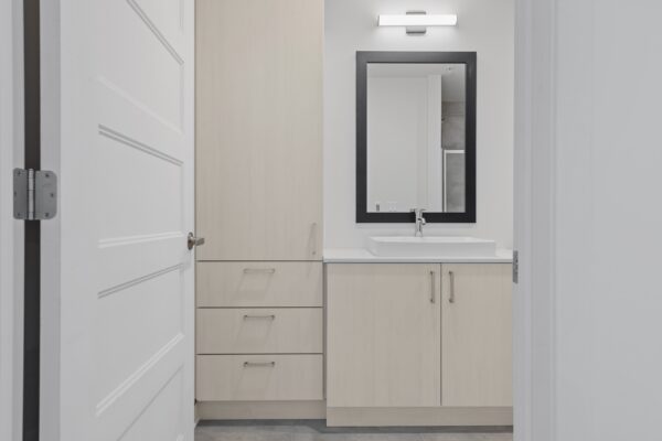 Meuble de salle de bain blanc avec miroir dans un appartement à Lachute, idéal pour la gestion immobilière.