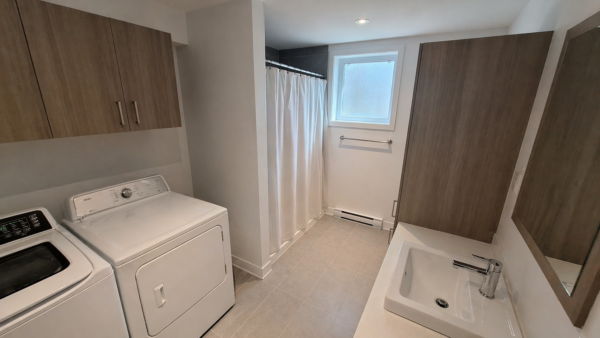 Vue intérieure d'un appartement d'une chambre à Pointe-aux-Trembles, avec buanderie, salle de bain et espace lumineux, idéal pour location ou résidence.
